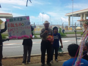 花束と泡盛のプレゼントをもらって喜びのごあいさつ